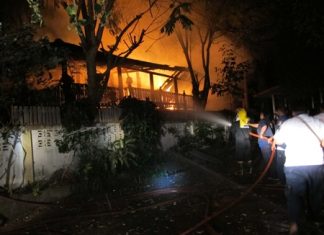 Firefighters use four fire engines to fight the blaze to prevent the wooden-house fire from spreading to neighboring homes.